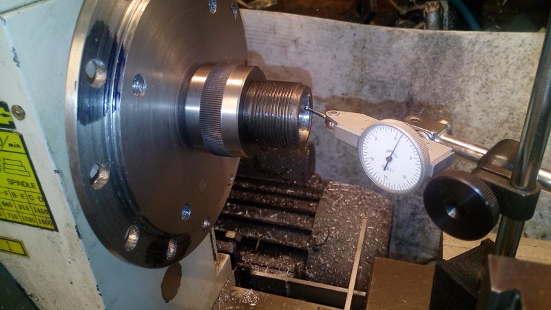 Dial test indicator touching a collet holder in a lathe spindle