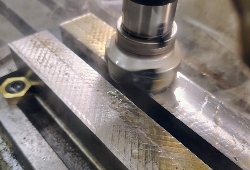 Indexable face mill cutting a steel bar on a milling machine