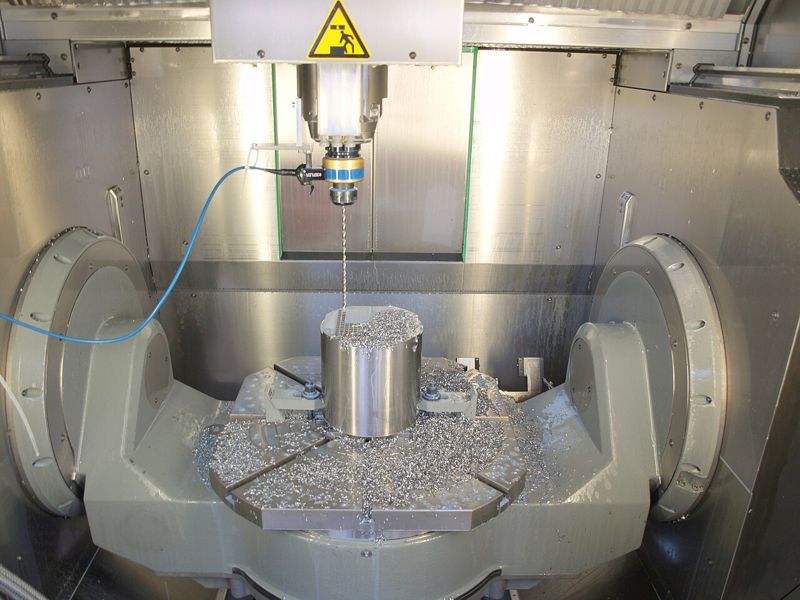 Inside a machining center: spindle and tool above a part during a drilling test