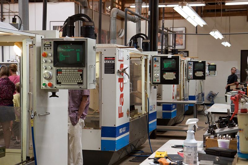 A row of vertical machining centers with their control pendants in a factory